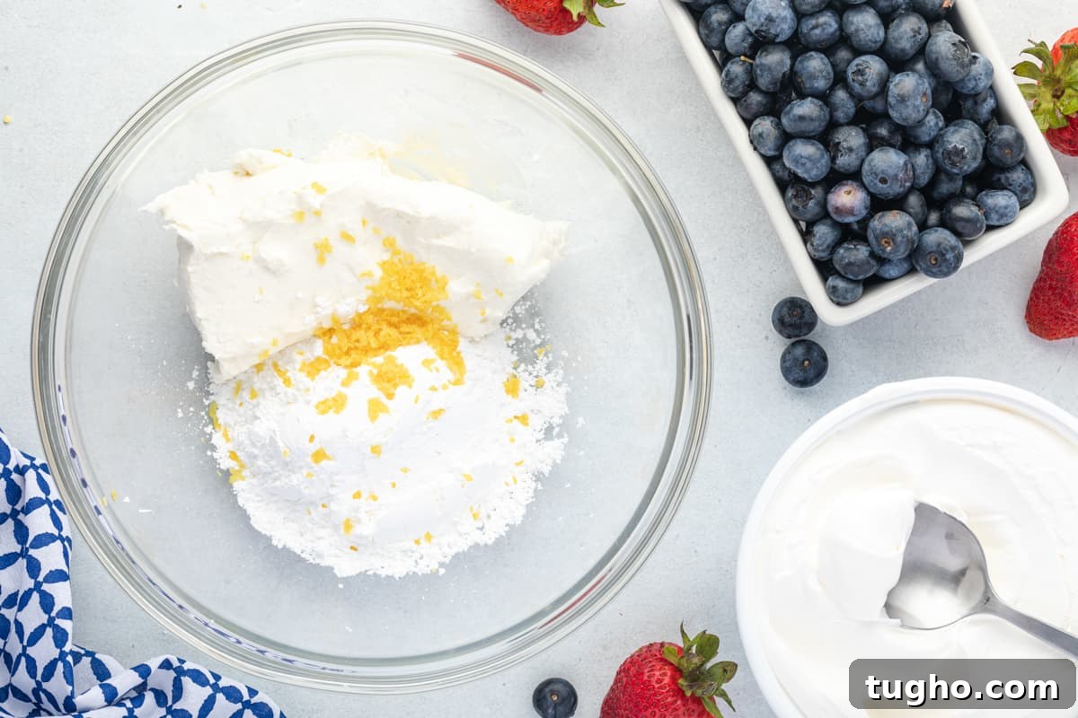 Patriotic Red, White and Blue Cheesecake Salad Recipe 10 cream cheese, lemon zest, and powdered sugar in a mixing bowl