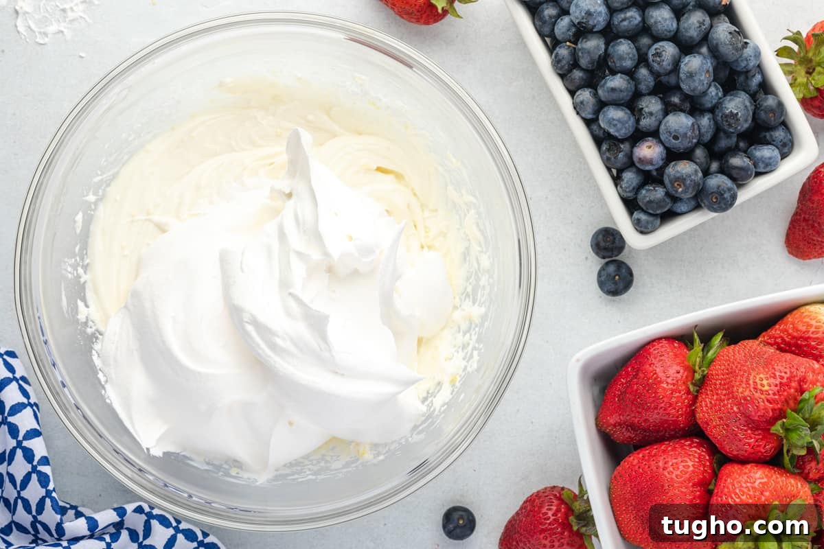Patriotic Red, White and Blue Cheesecake Salad Recipe 11 cheesecake filling and whipped topping in a mixing bowl