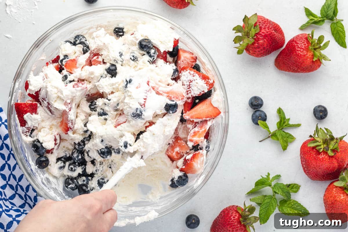 Patriotic Red, White and Blue Cheesecake Salad Recipe 12 Folding blueberries and strawberries into a cream cheese mixture.