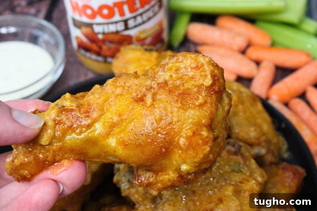 holding up an air fryer hooters wing drumstick in front of carrots and celery