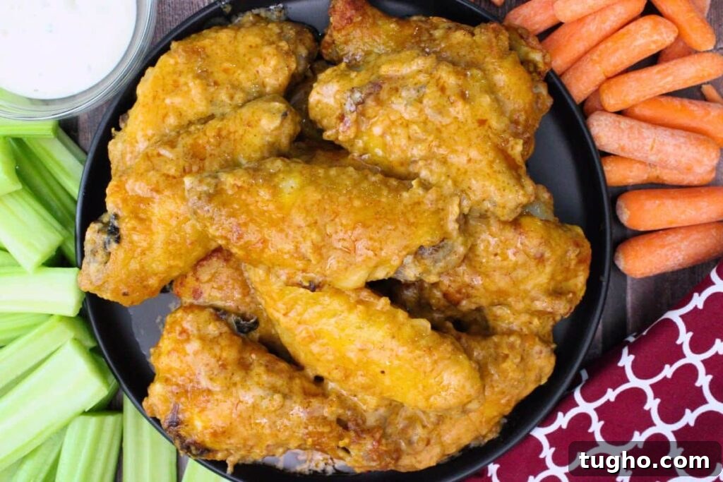 overhead view of copycat air fryer hooters wings on a plate surrounded by carrots and celery