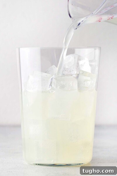 Layered Matcha Lemonade Recipe: Iced Citrus Green Tea 7 Pouring lemonade in a cup with ice.