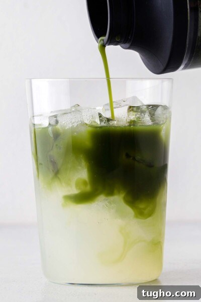 Layered Matcha Lemonade Recipe: Iced Citrus Green Tea 8 Pouring matcha into a cup with lemonade and ice.