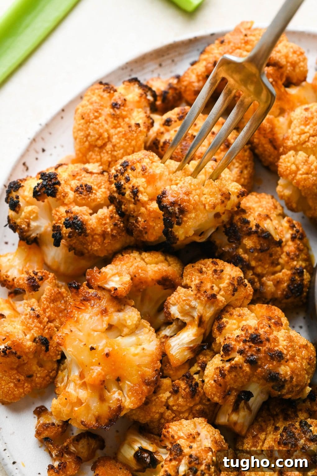 Roasted Buffalo Cauliflower Recipe (Dairy-Free) 12 A fork piercing a single roasted buffalo cauliflower floret.