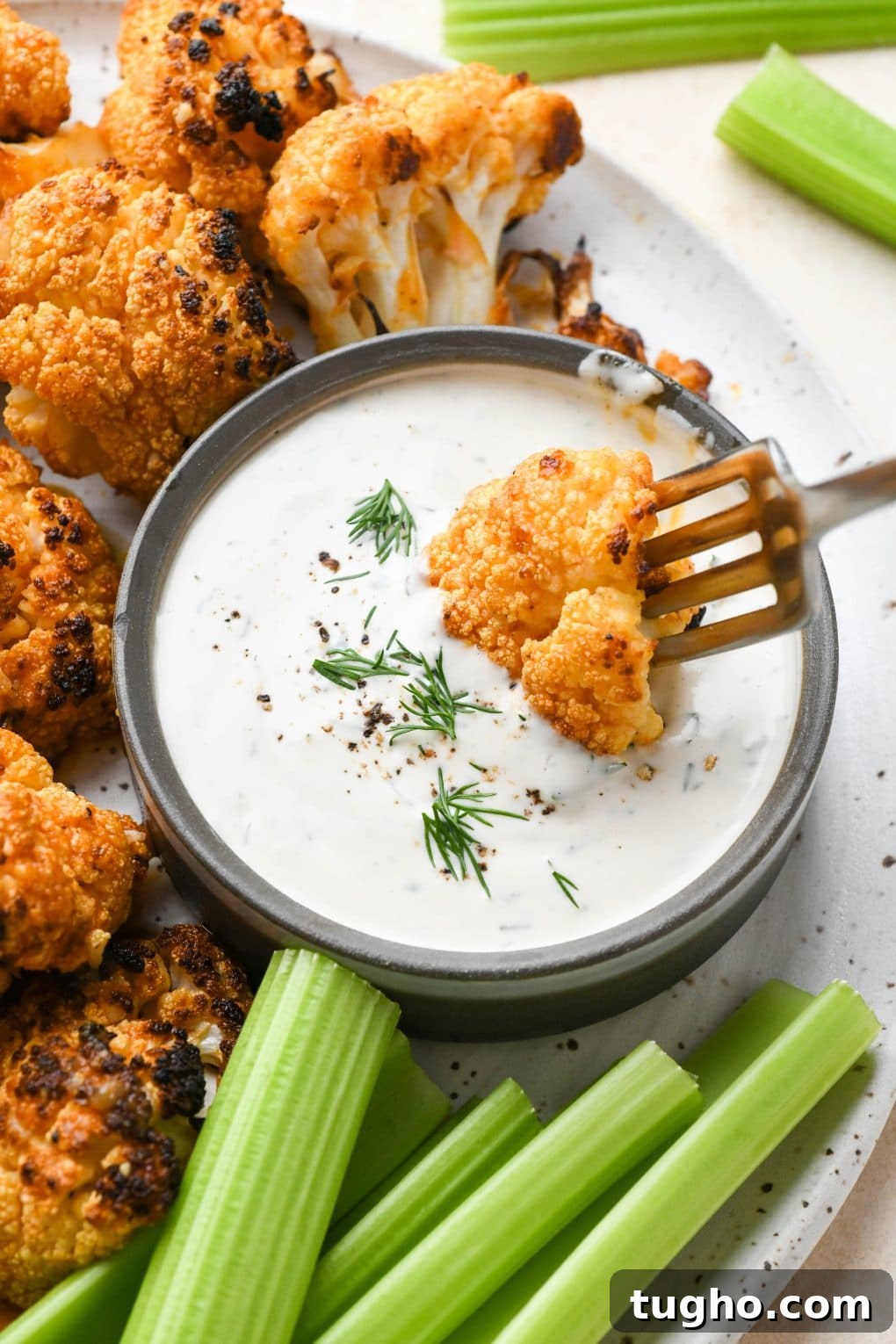 Roasted Buffalo Cauliflower Recipe (Dairy-Free) 13 A fork dipping a buffalo cauliflower floret into vegan ranch dressing.