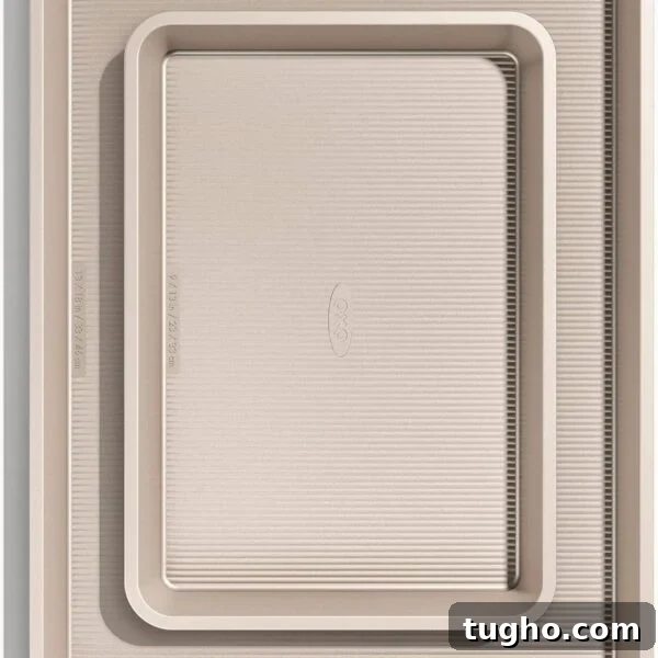 Two beige, non-stick baking sheets of two sizes are stacked.
