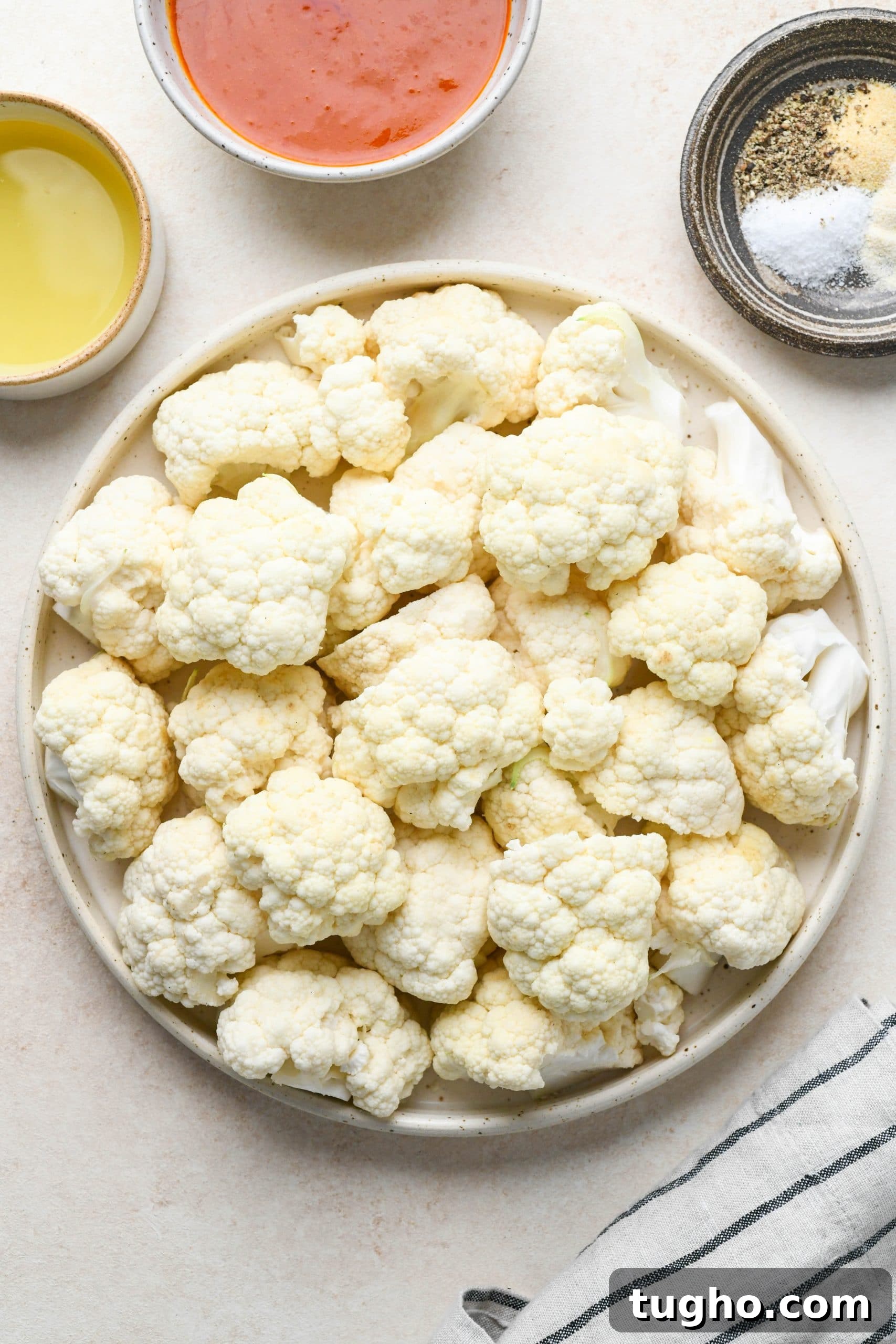 Roasted Buffalo Cauliflower Recipe (Dairy-Free) 4 Ingredients for buffalo cauliflower in various ceramics on a light cream colored background.