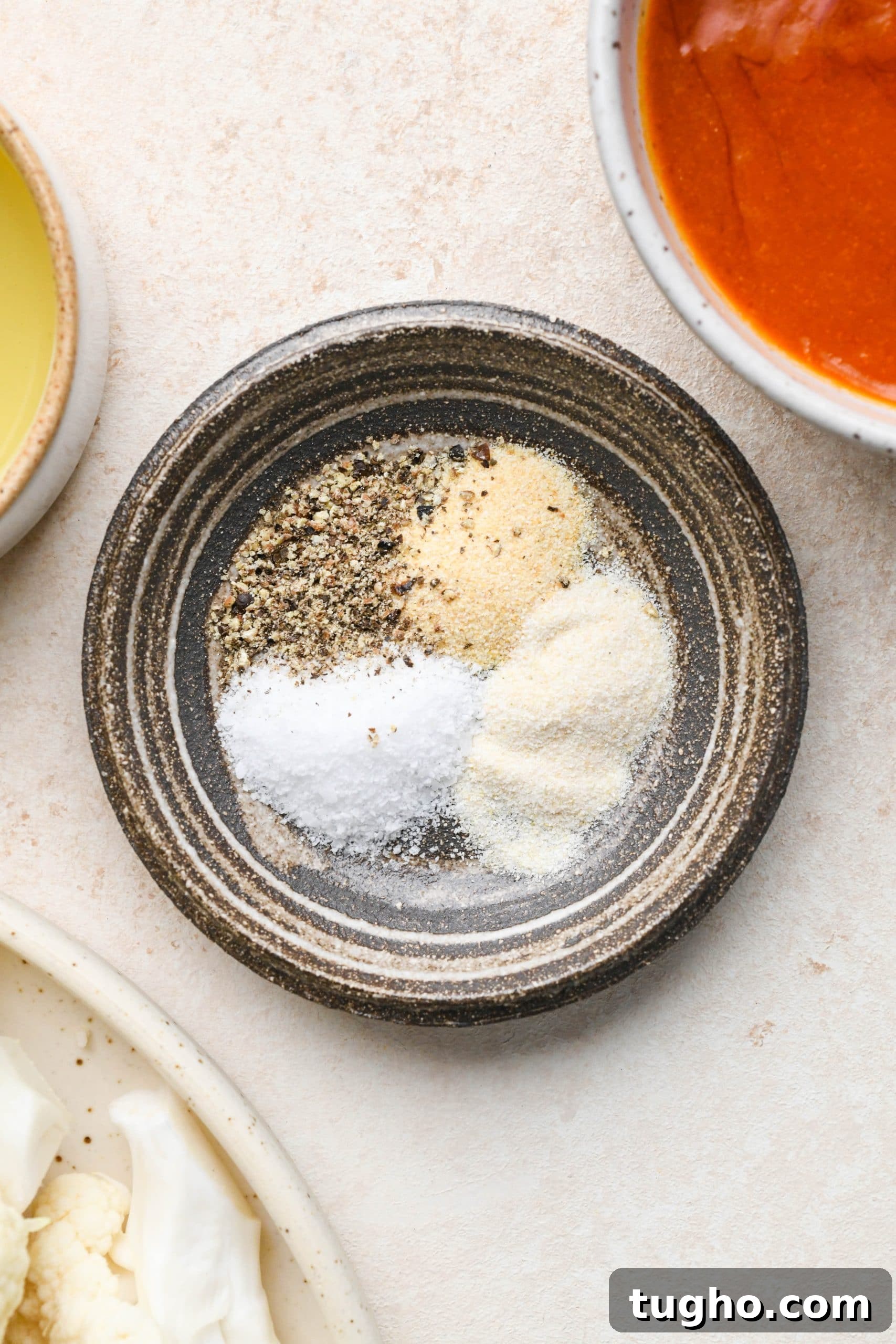 Roasted Buffalo Cauliflower Recipe (Dairy-Free) 5 Spices for buffalo cauliflower in a small ceramic dish
