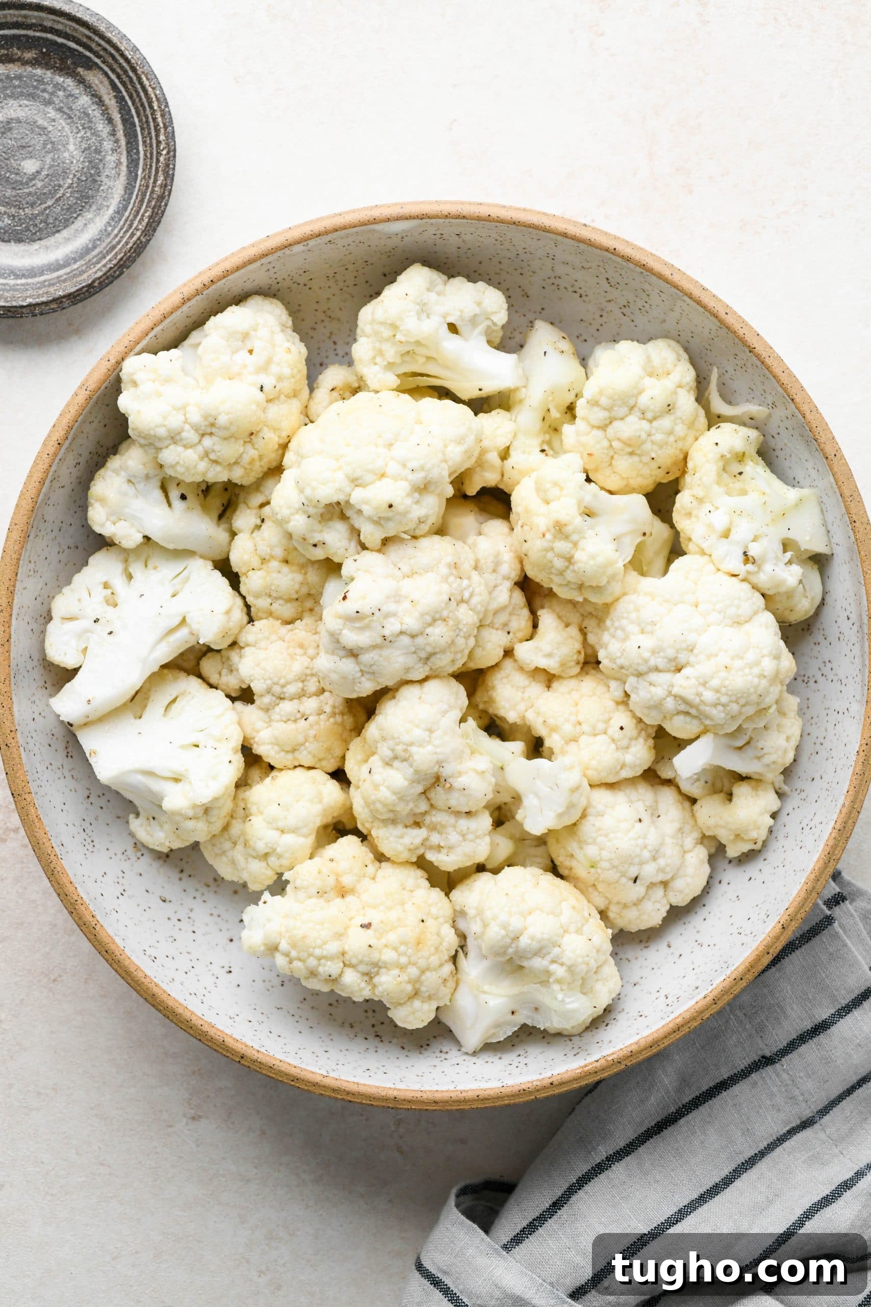 Roasted Buffalo Cauliflower Recipe (Dairy-Free) 6 How to make buffalo cauliflower: Raw cauliflower florets in a bowl tossed with oil and spices.