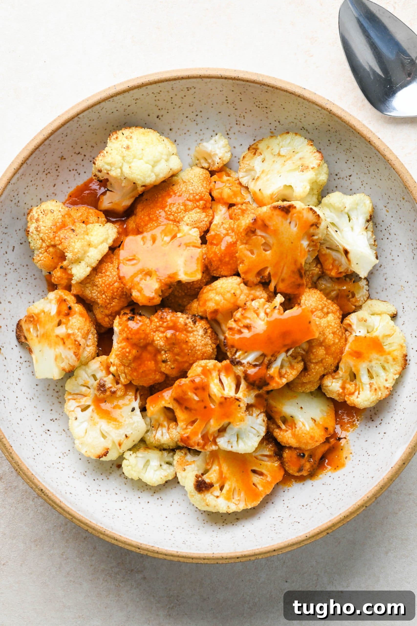 Roasted Buffalo Cauliflower Recipe (Dairy-Free) 8 How to make buffalo cauliflower: Roasted cauliflower florets in a bowl topped with buffalo sauce.