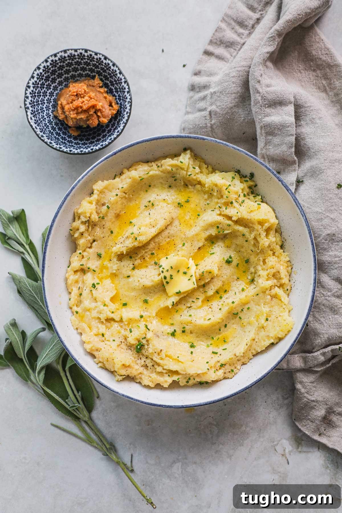 Umami Miso Mashed Potatoes Recipe 2 Creamy, fluffy miso mashed potatoes with miso sage butter served in a serving dish with sage leaves and a bowl of miso.