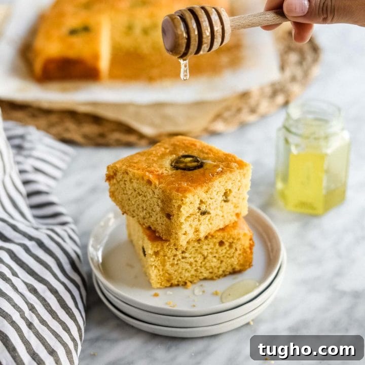 Jalapeño Cheddar Cornbread with Miso sliced on plate with butter and honey.