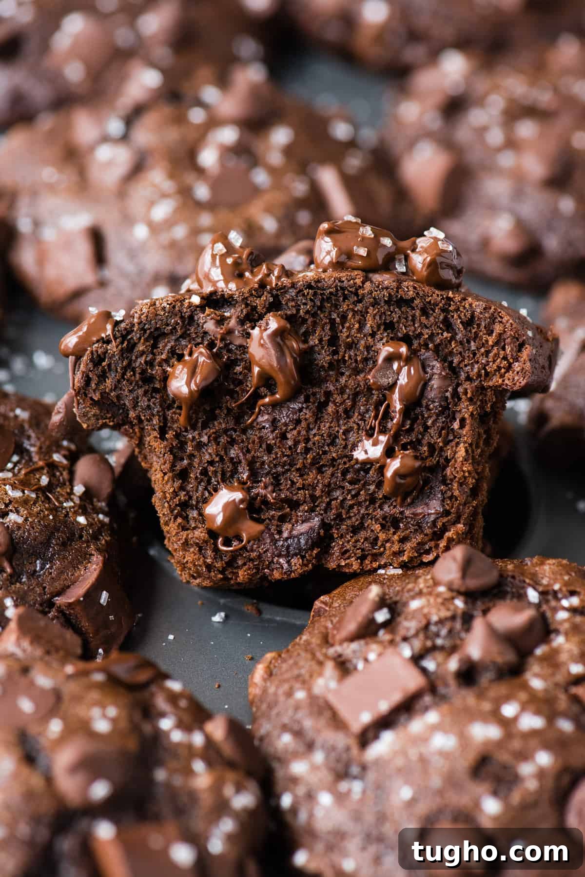 chocolate muffin cut in half to show melty chocolate chips in metal muffin pan