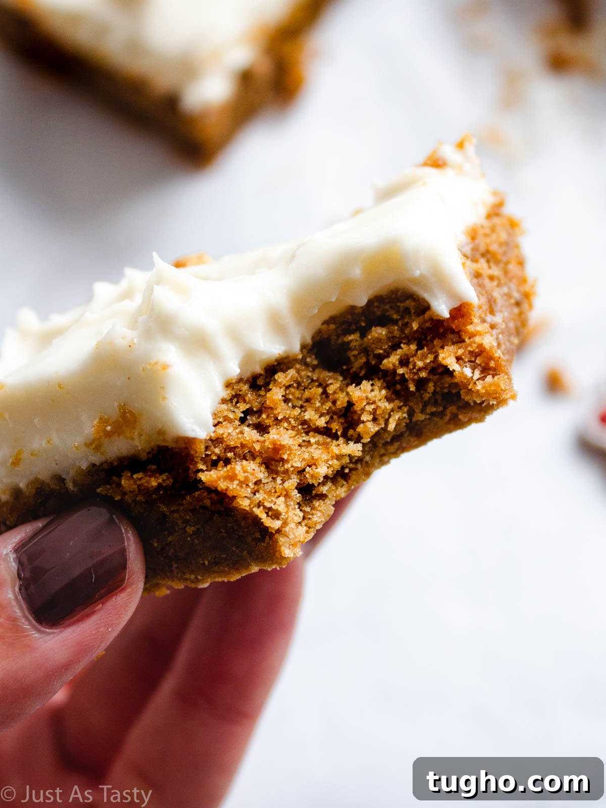 Soft, Chewy Gingerbread Bars with Cream Cheese Frosting 3 Close-up of a frosted gingerbread bar with a bite taken out.