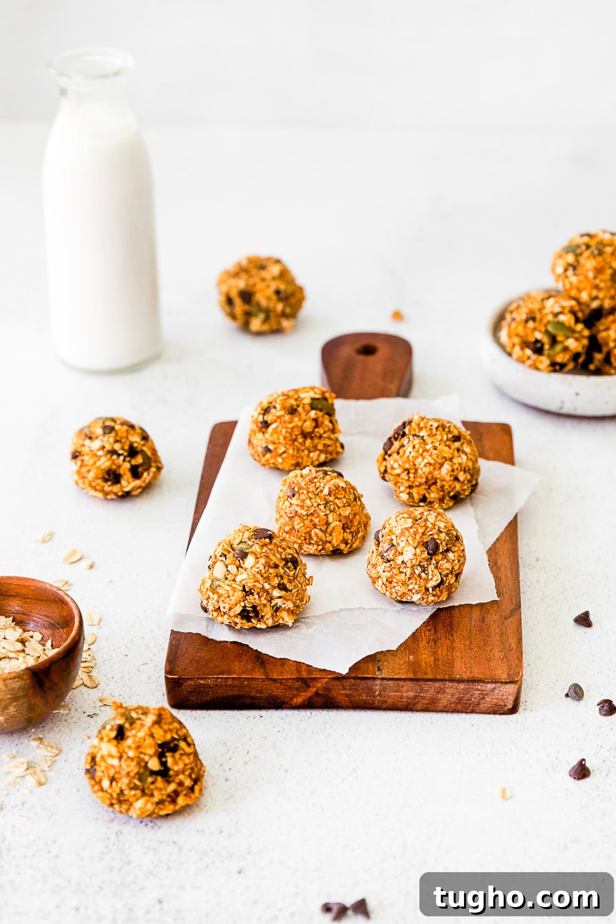 Pumpkin Energy Balls sitting on parchment paper on a wooden cutting board.