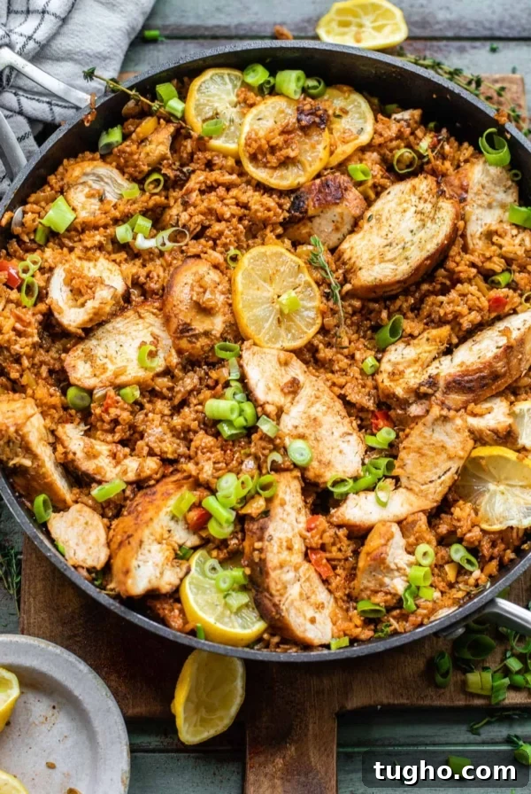cajun chicken and rice in a skillet with lemons and fresh herbs