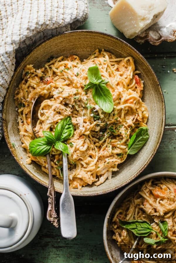 overhead photo of slow cooker chicken spaghetti in a bowl garnished with parsley and basil.