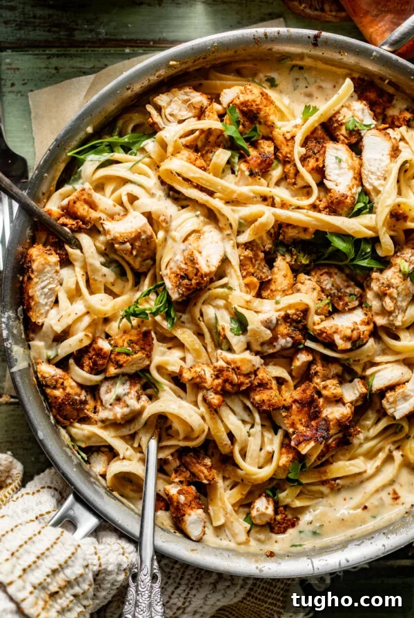 blackened chicken alfredo in a skillet topped with parsley.
