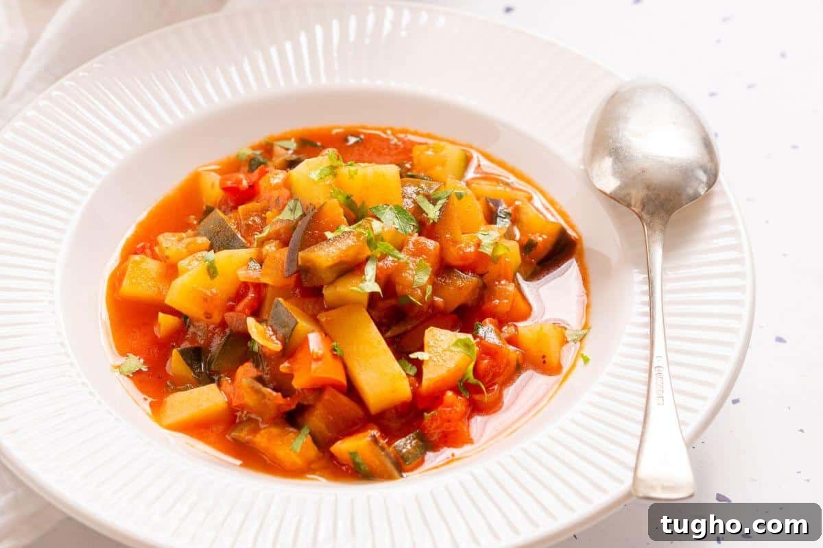 A pot of Italian vegetable stew with a spoon, garnished with chopped green herbs, on a white tablecloth with a small bowl of parsley on the side.
