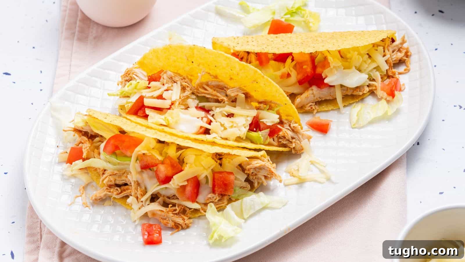 Two tacos on a plate with a bowl of guacamole.