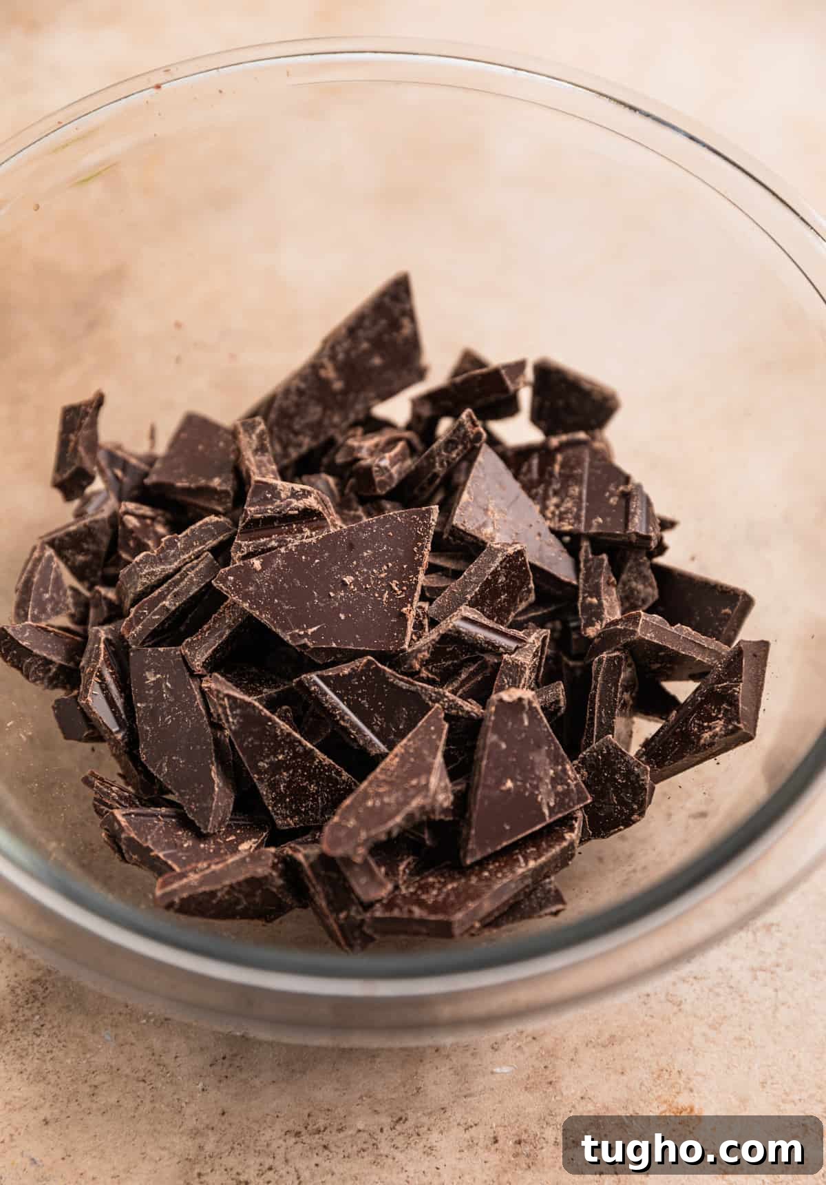 Chopped dark chocolate in glass bowl.