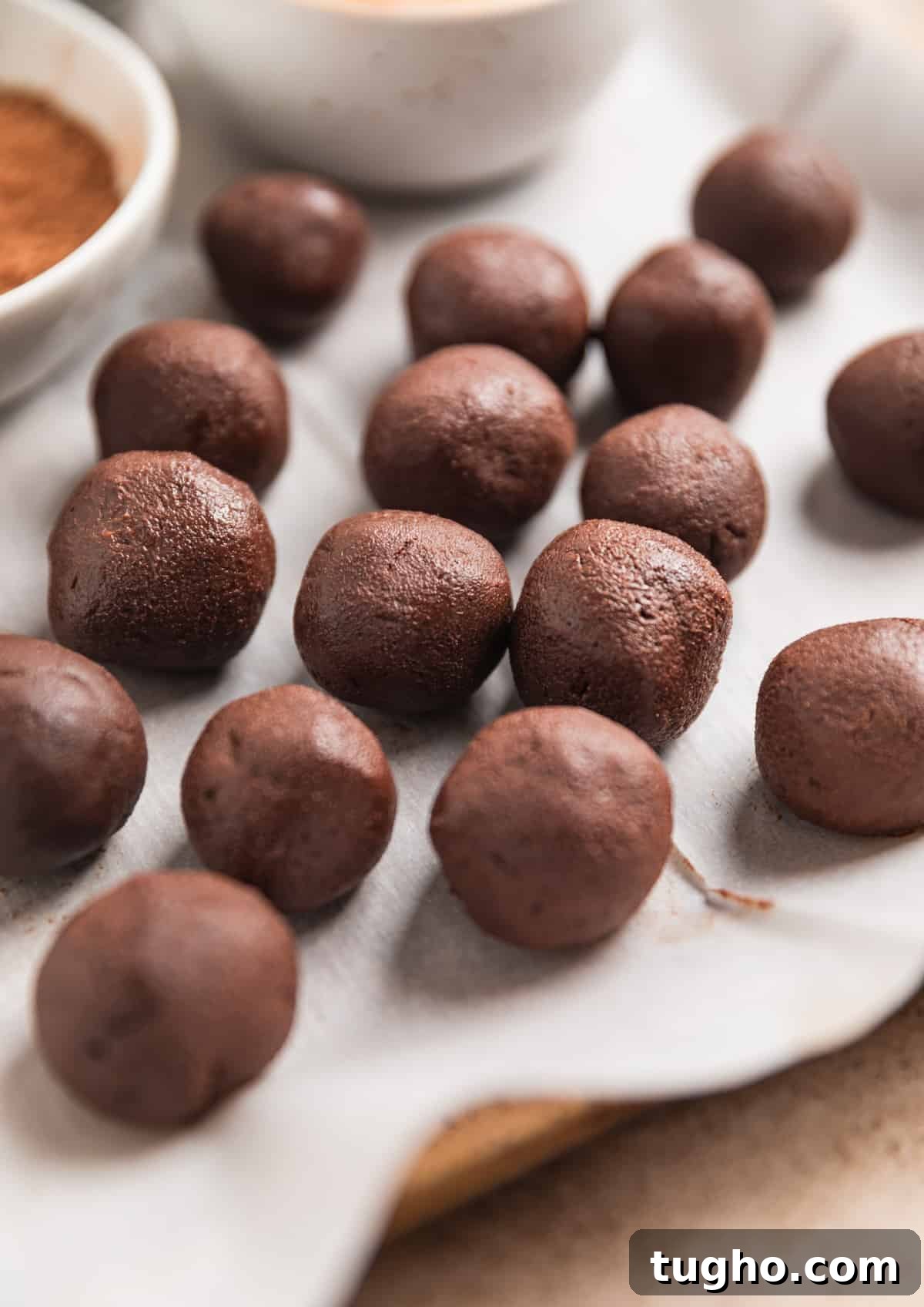 Chocolate truffles rolled and laying on parchment paper.