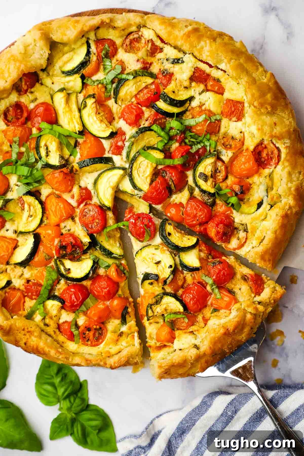 Overhead view of a zucchini tomato tart with one slice being removed.