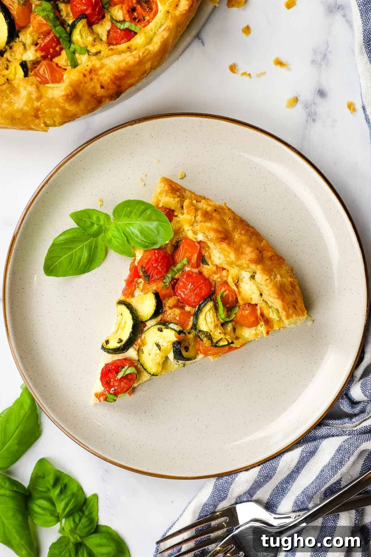 an overview of a slice of zucchini tomato tart on a plate