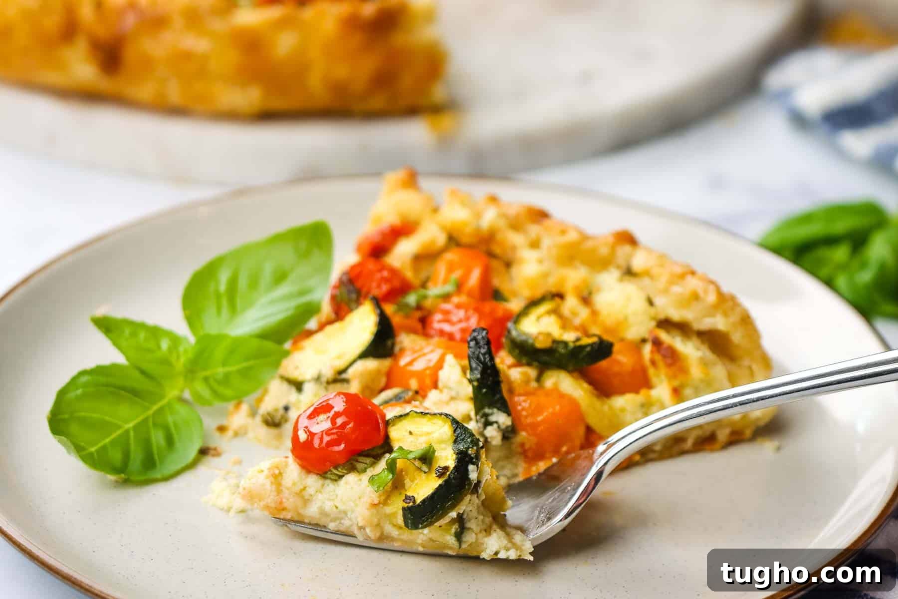 cutting into a slice of zucchini tomato tart with a fork