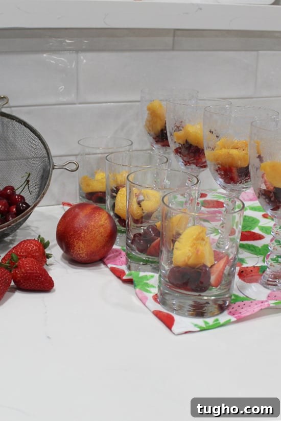 Fresh fruit in clear glasses waiting for the gelatin to be poured in.