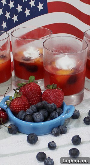 Strawberries and blueberries showcased with desserts in clear glasses.