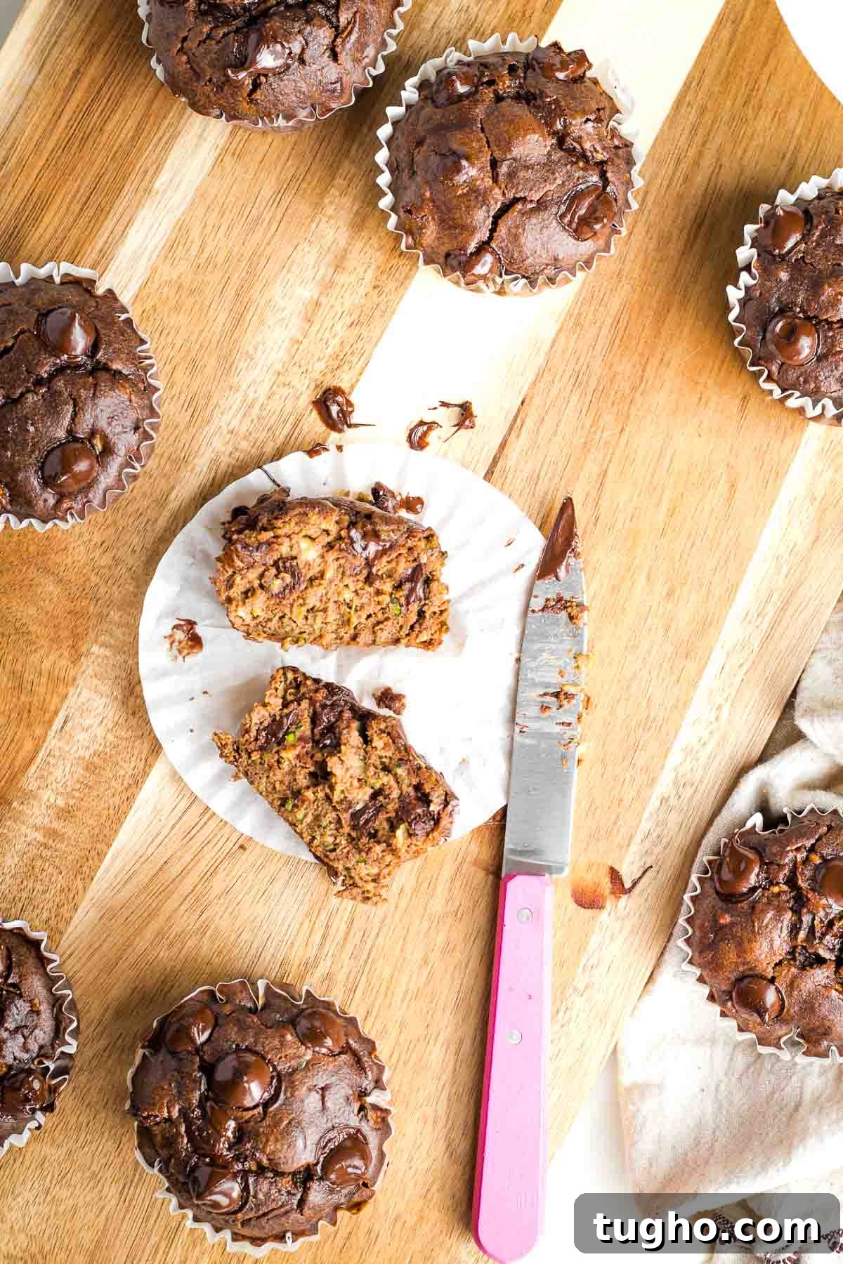 Fudgy Double Chocolate Zucchini Muffins Recipe 2 Chocolate muffin with chocolate chips cut in half in the paper wrapper.