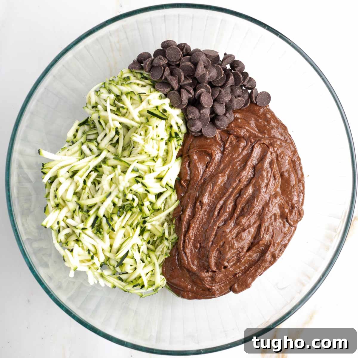 Fudgy Double Chocolate Zucchini Muffins Recipe 8 Chocolate batter, chocolate chips and shredded zucchini in a large glass mixing bowl.