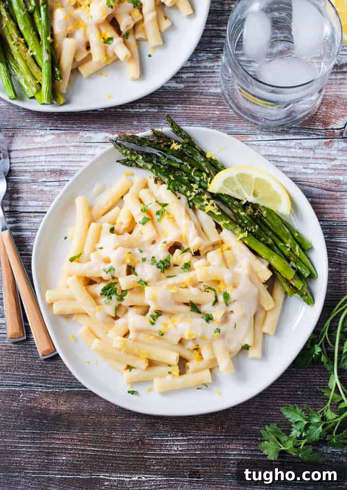Overhead view of pasta in a vegan white sauce with a side of roasted asparagus.