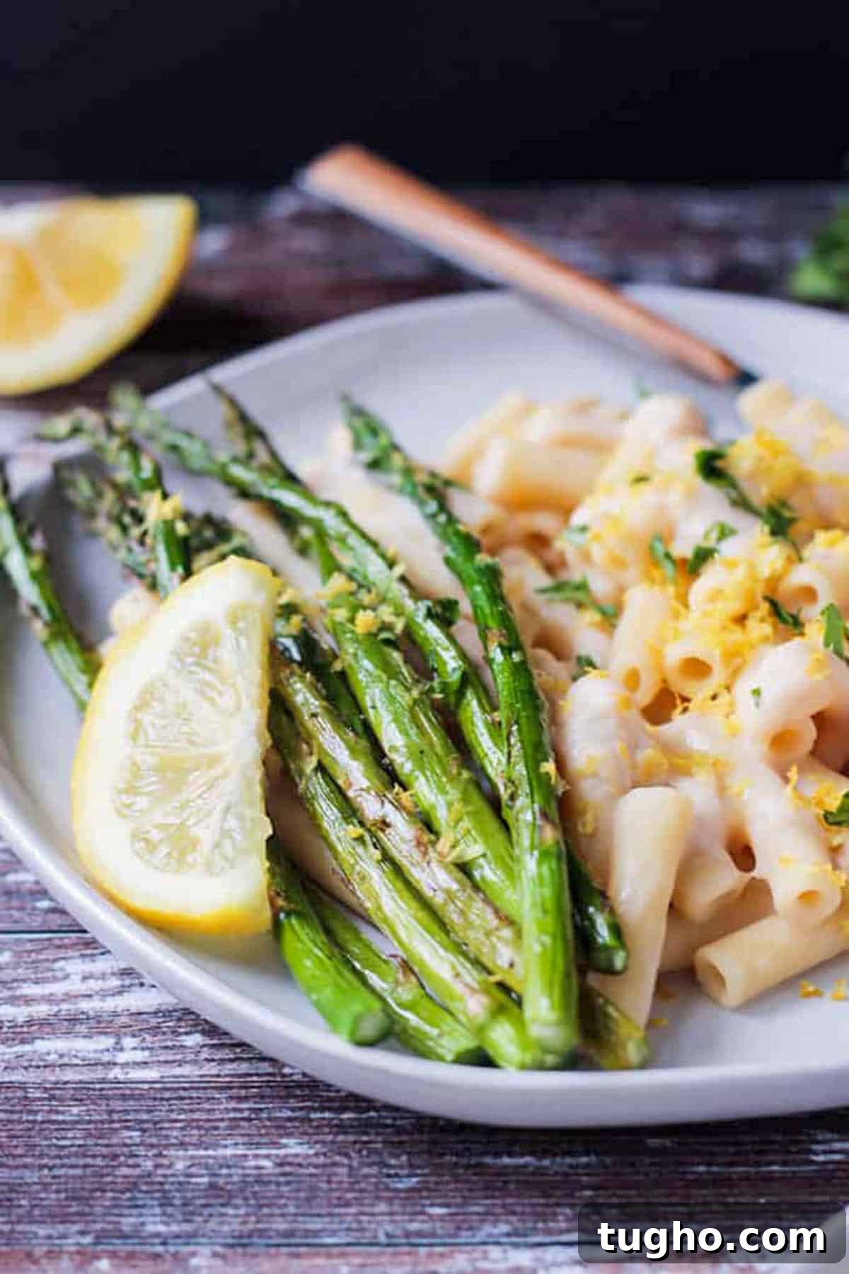 Close up of roasted asparagus topped with lemon zest and a lemon wedge.