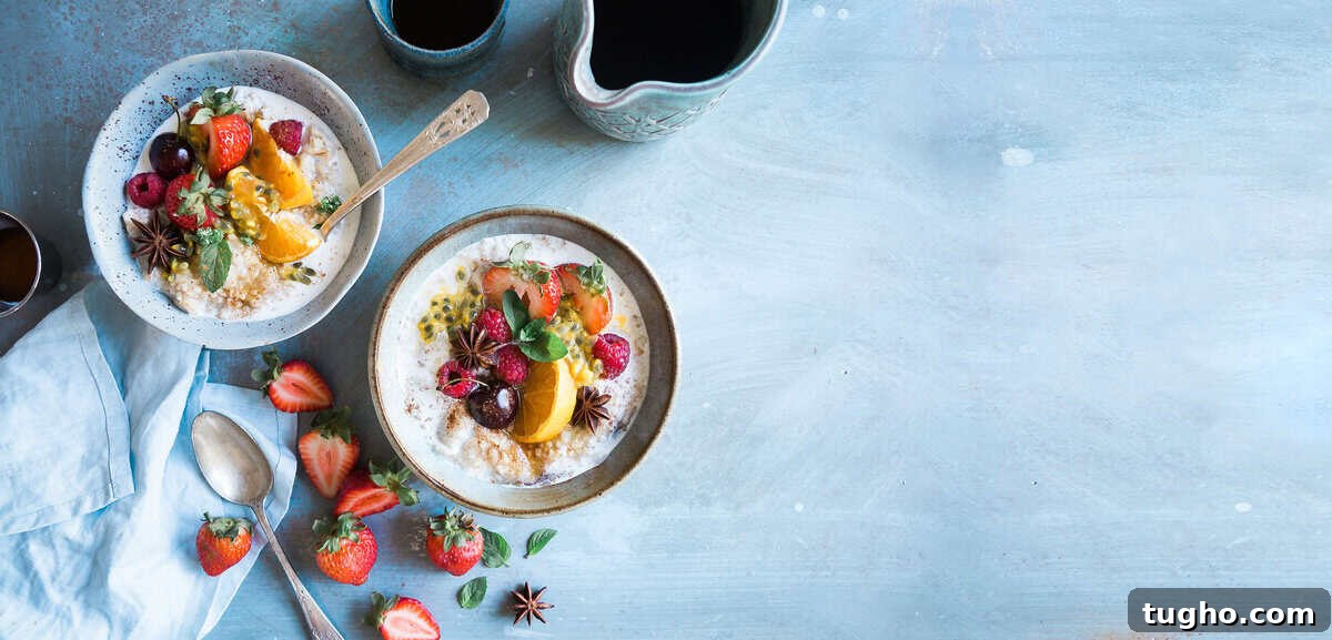 Fresh fruit breakfast bowls with strawberries, oranges, and raspberries on a light blue background.