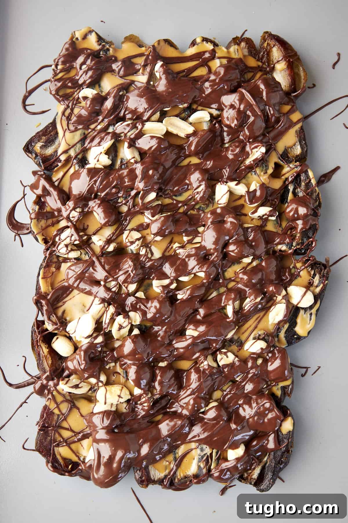 Viral TikTok Date Bark Recipe: Chocolate and Nuts 4 Dates topped with peanut butter, peanuts, and melted chocolate.