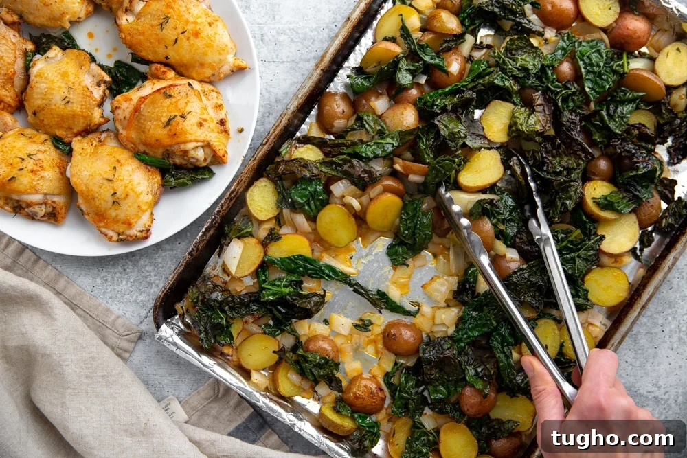 Crispy Sheet Pan Roasted Chicken with Vegetables 7 Process shot showing tongs stirring the sheet pan veggies halfway through the cooking time, with the chicken thighs on a plate alongside.