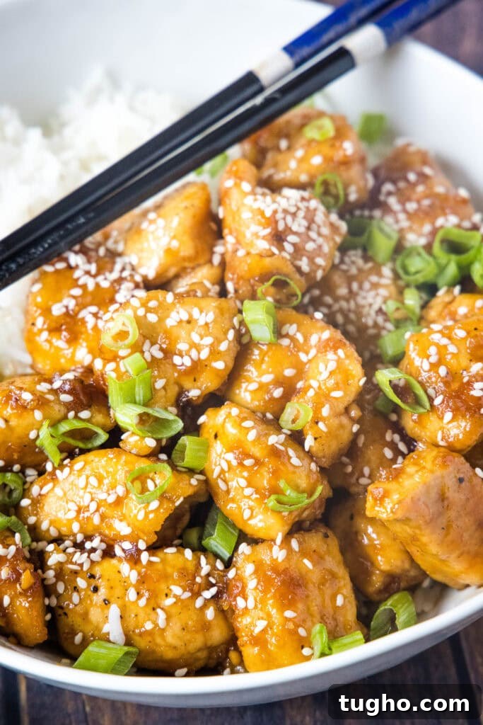 bourbon chicken in a bowl with rice and chopsticks
