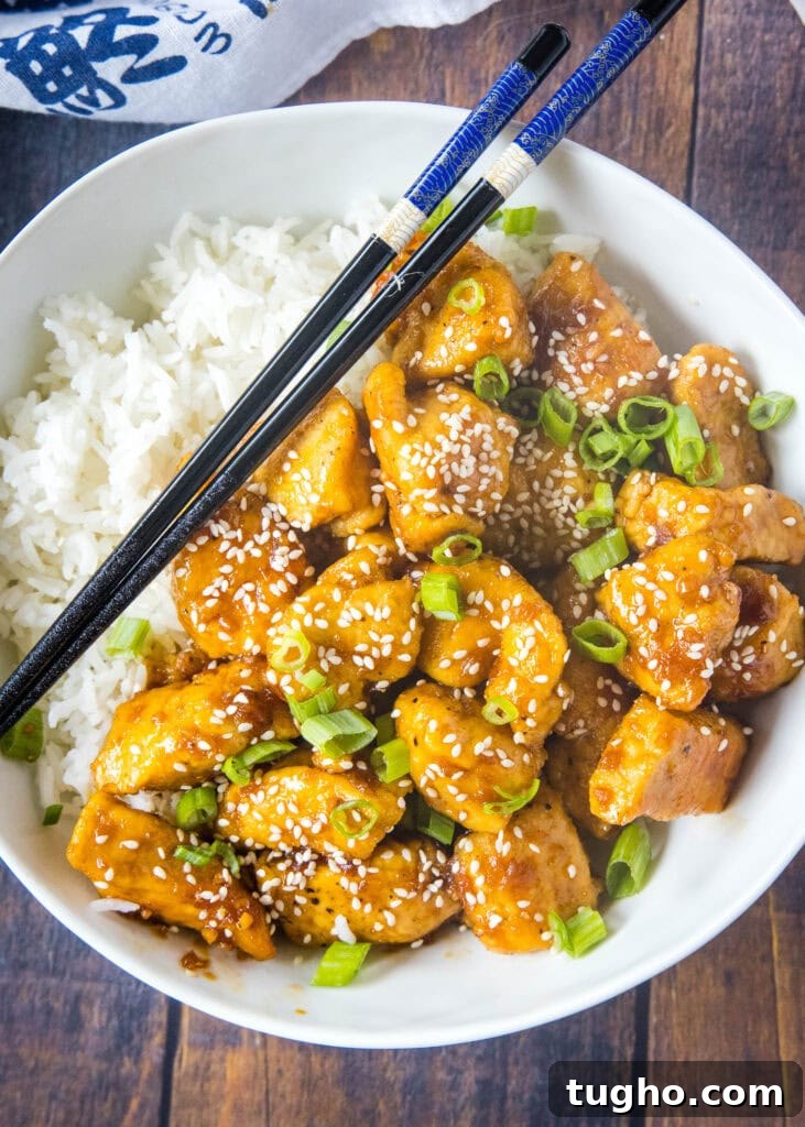 looking down on a white bowl with rice and bourbon chicken