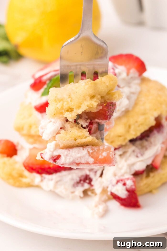 Classic Vegan Strawberry Shortcake Recipe 15 Fork with a forkful of strawberry shortcake biscuit, whipped cream and strawberry.