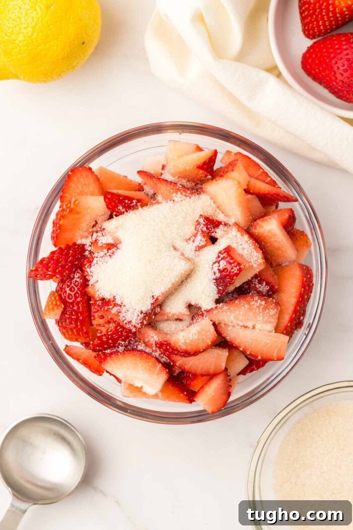 Classic Vegan Strawberry Shortcake Recipe 4 Sliced strawberries topped with sugar in a bowl.