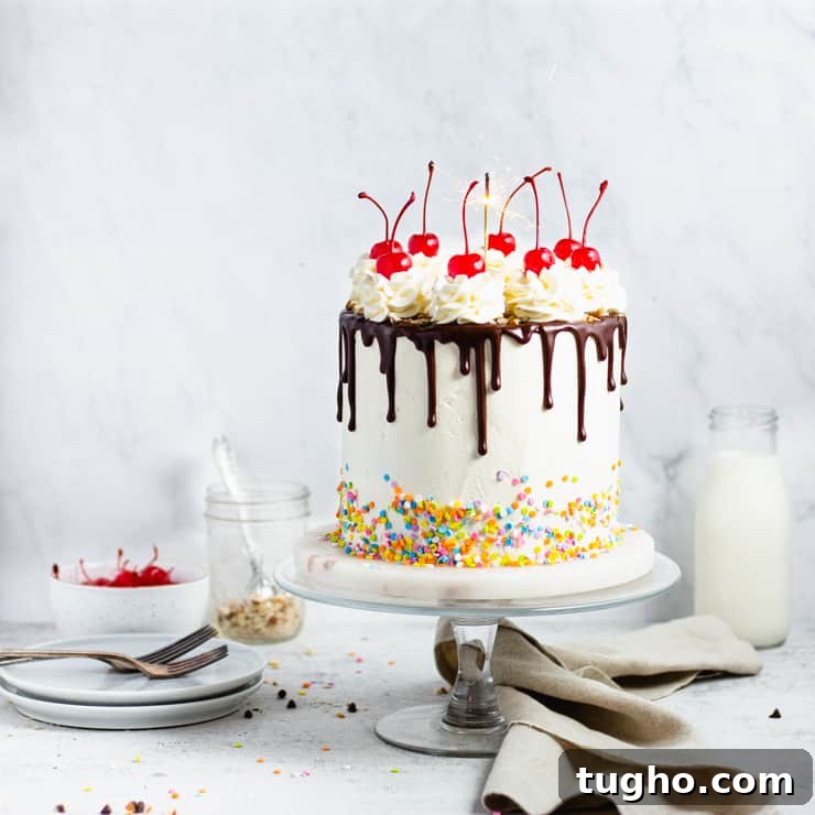 Indulgent Fudge Sundae Cake Recipe with Hot Fudge Sauce 4 fudge cake with a chocolate drip, cherries and sprinkles with a sparkler on top