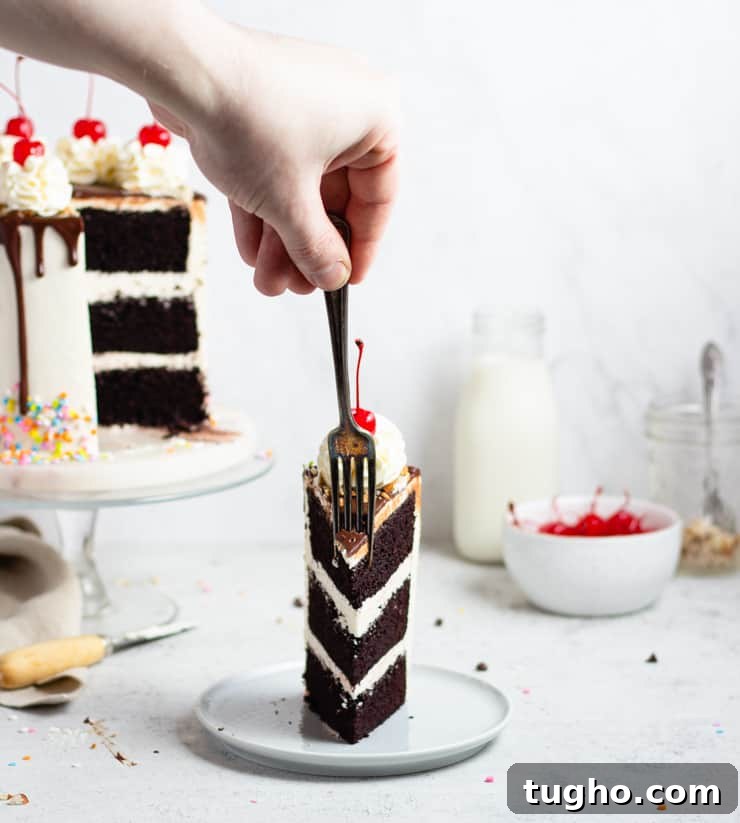 Indulgent Fudge Sundae Cake Recipe with Hot Fudge Sauce 5 Hand taking a fork-full of a cake slice