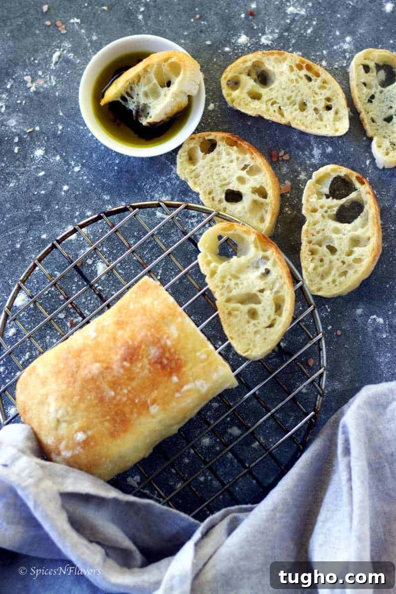 How to Make Authentic Ciabatta Bread at Home 9 ciabatta bread placed on a wire rack with few slices showing the texture within around it