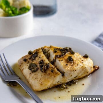 baked snapper topped with capers on white plate with fork