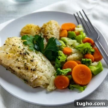 cooked cod on white plate with broccoli, cauliflower, and carrot mixture