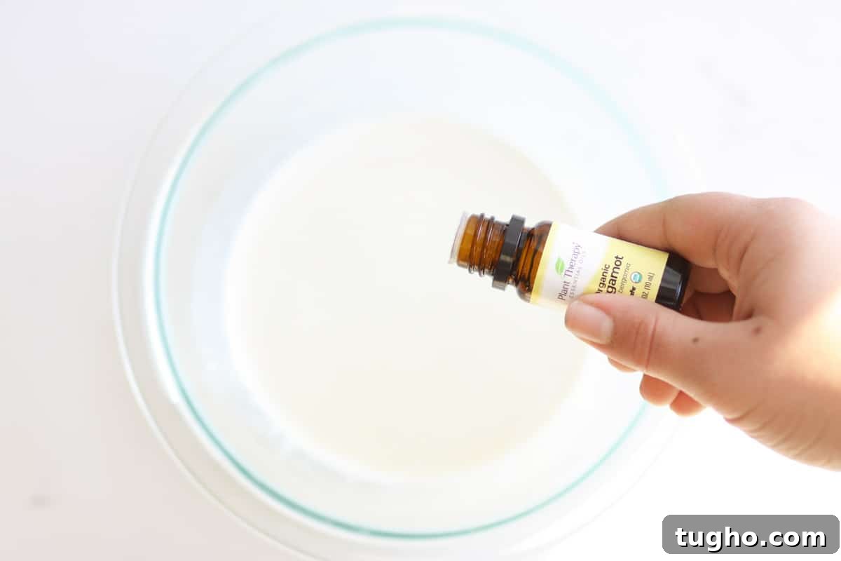 Bergamot essential oil being dripped into a bowl of liquid deodorant