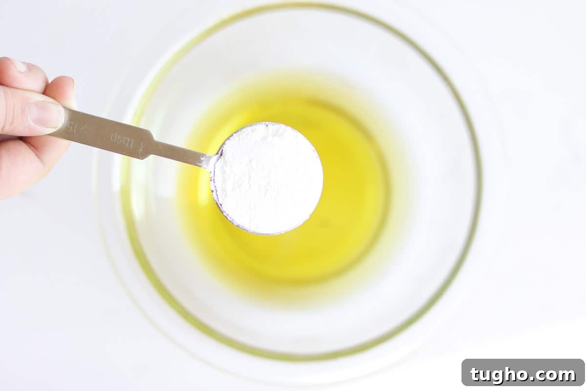 zinc oxide in a tablespoon being held over a bowl of melted oils