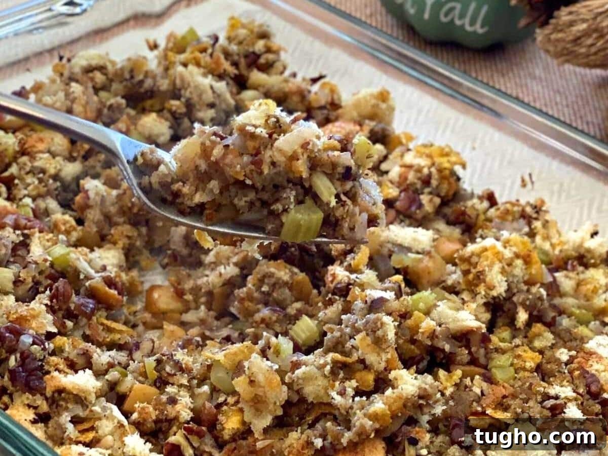 15 Make-Ahead Thanksgiving Recipes to Prep Now 2 Spoon lifting stuffin with apples, celery, and pecans out of a glass baking dish.